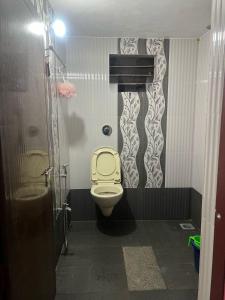 a bathroom with a toilet with a yellow seat at Silent River Homestay in Perdūru