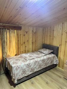 a bed in a room with a wooden wall at In the Forest in K'vemo Jocho