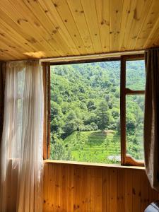 a window in a wooden room with a mountain view at In the Forest in K'vemo Jocho