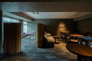 a living room with tables and a couch and chairs at BbyC HOTEL Kusatsu in Kusatsu