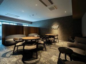 a waiting room with tables and chairs and a chandelier at BbyC HOTEL Kusatsu in Kusatsu +78 photos