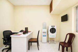 a room with a desk and a heater and chairs at FabHotel Mara Residency in Chennai