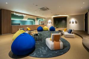 a lobby with a room with blue and yellow chairs at BbyC HOTEL Kusatsu in Kusatsu