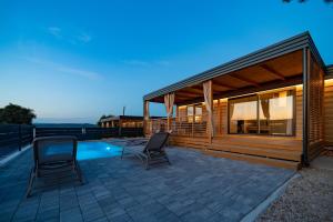 a patio with two chairs and a house at Camping Nevia - Mobile Homes with Heated Private Pool in Neviđane