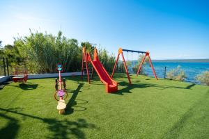 a playground with a red swing set on the grass at Camping Nevia - Mobile Homes with Heated Private Pool in Neviđane