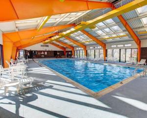 a large swimming pool with white chairs and an orange ceiling at Comfort Inn Conference Center Pittsburgh Penn Hills in Churchill