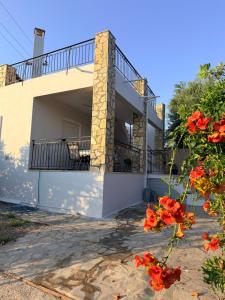 a house with a balcony and red flowers at Maison Pelops Petalidi in Petalidi