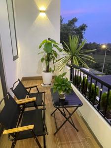 two chairs and a table on a balcony with plants at Mẹ Nhím homestay in Chung Cap