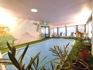 a swimming pool in a room with plants and a mural at chambres d hôtes chez Isabelle in La Ferté-Saint-Cyr
