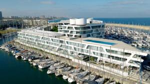 a large white building with boats in a marina at The YACHT - By Fattal Limited Edition in Herzliya B