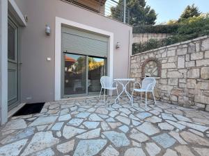 a patio with chairs and a table and a stone wall at The nest in Kalavrita