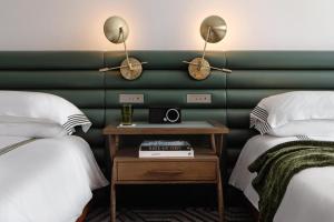 a hotel room with two beds and a table with a clock at Thompson Houston, by Hyatt in Houston