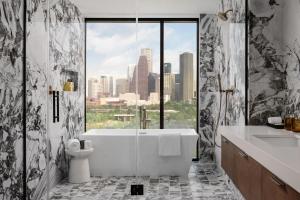 a bathroom with a tub and a view of the city at Thompson Houston, by Hyatt in Houston +98 photos