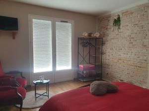 a bedroom with a red bed and a brick wall at La Tuilerie Lixy Brannay in Brannay