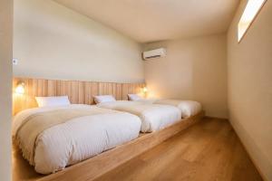 two beds in a hotel room with wood floors at Villa KULM in Minamiawaji
