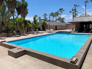 a swimming pool with chairs and umbrellas at a resort at Loreto Playa Boutique Hotel in Loreto