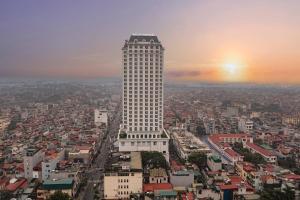 a tall white building in the middle of a city at Meliá Vinpearl Phu Ly in Phủ Lý