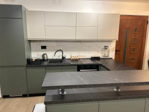 a kitchen with white cabinets and a black counter top at Maginja house in Milojci