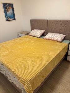 a bed with a yellow blanket on top of it at Maginja house in Milojci