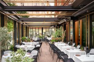 a restaurant with white tables and chairs and windows at Matild Palace, a Luxury Collection Hotel in Budapest