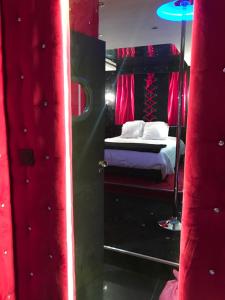 1 dormitorio con 1 cama con cortinas rojas y espejo en Le Cabaret Vip SPA en Lyon