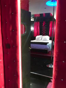 a bedroom with a bed with red curtains and a mirror at Le Cabaret Vip SPA in Lyon