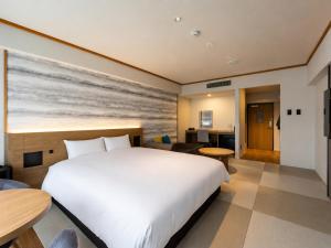 a bedroom with a large bed and a living room at BbyC HOTEL Kusatsu in Kusatsu