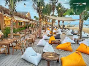 a row of tables and chairs with pillows on a beach at VILLA NOVAWORLD PHAN THIET Beach in Phan Thiet