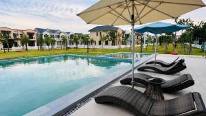 a swimming pool with chairs and an umbrella at VILLA NOVAWORLD PHAN THIET Beach in Phan Thiet