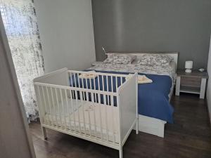 a white crib in a bedroom with a bed at Lucija in Pridraga