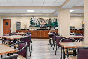 a dining room with tables and chairs and a kitchen at Big Horn Resort, an Ascend Collection Hotel in Billings