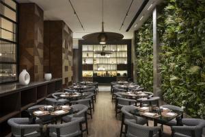 a restaurant with tables and chairs and plants at DoubleTree by Hilton Madinah Gate in Medina