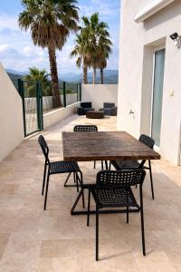 a wooden table and chairs on a patio with palm trees at Les vacances in Sainte-Maxime