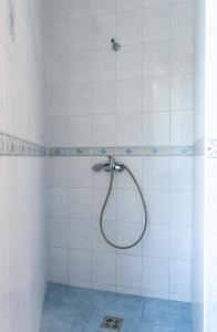 a shower with a hose in a white tiled bathroom at Green House in Banka