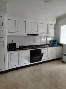 a kitchen with white cabinets and a stove top oven at VIVIENDA TURÍSTICA Bajo, 7 Escaleras in Laxe +11 photos