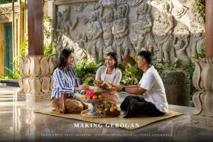 a group of three people sitting in front of a statue at ULU Valley Retreat in Tegalalang
