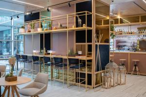 a room with a bar with chairs and tables at INNSiDE by Meliá Milano Torre GalFa in Milan