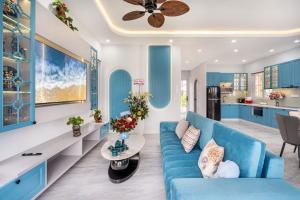 a living room with a blue couch and a kitchen at VILLA NOVAWORLD PHAN THIET Beach in Phan Thiet