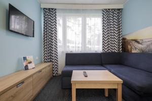 a living room with a blue couch and a coffee table at Hotel *** NAT Krynica Morska in Krynica Morska