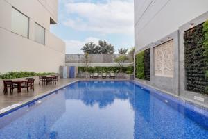 an outdoor swimming pool with a table and chairs at Lemon Tree Hotel, Sector 60, Gurugram in Gurgaon