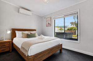 a white bedroom with a bed and a window at Solander in Dromana with Private Spa by Ready Set Stay in Dromana