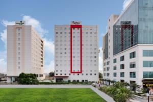 two tall white buildings with a red stripe on them at Lemon Tree Hotel, Sector 60, Gurugram in Gurgaon