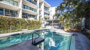 a swimming pool in front of a building at Whispering Waves On Boyd in Woorim