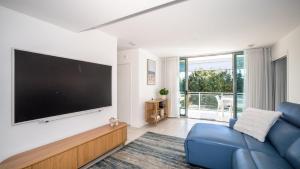 a living room with a large tv and a blue couch at Whispering Waves On Boyd in Woorim