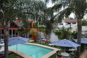 una piscina con ombrelloni e sedie e una casa di Costas del Paraiso a Colón