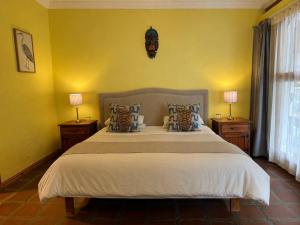 a bedroom with a large bed with yellow walls at Oakdene Guest House in Oudtshoorn
