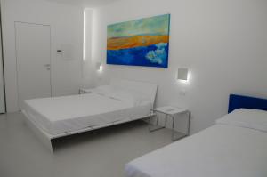 Habitación blanca con 2 camas y una pintura en la pared. en Portopalosuite, en Portopalo di Capo Passero
