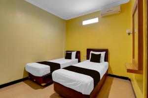 two beds in a room with yellow walls at Hotel O near Alun-Alun Kidul formerly Ndalem Mantrijeron Hotel in Yogyakarta