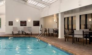 a pool with chairs and tables in a building at Hampton Inn Boston Logan Airport in Boston