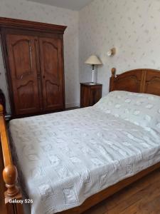 a bedroom with a bed and a wooden cabinet at maison village in Xambes